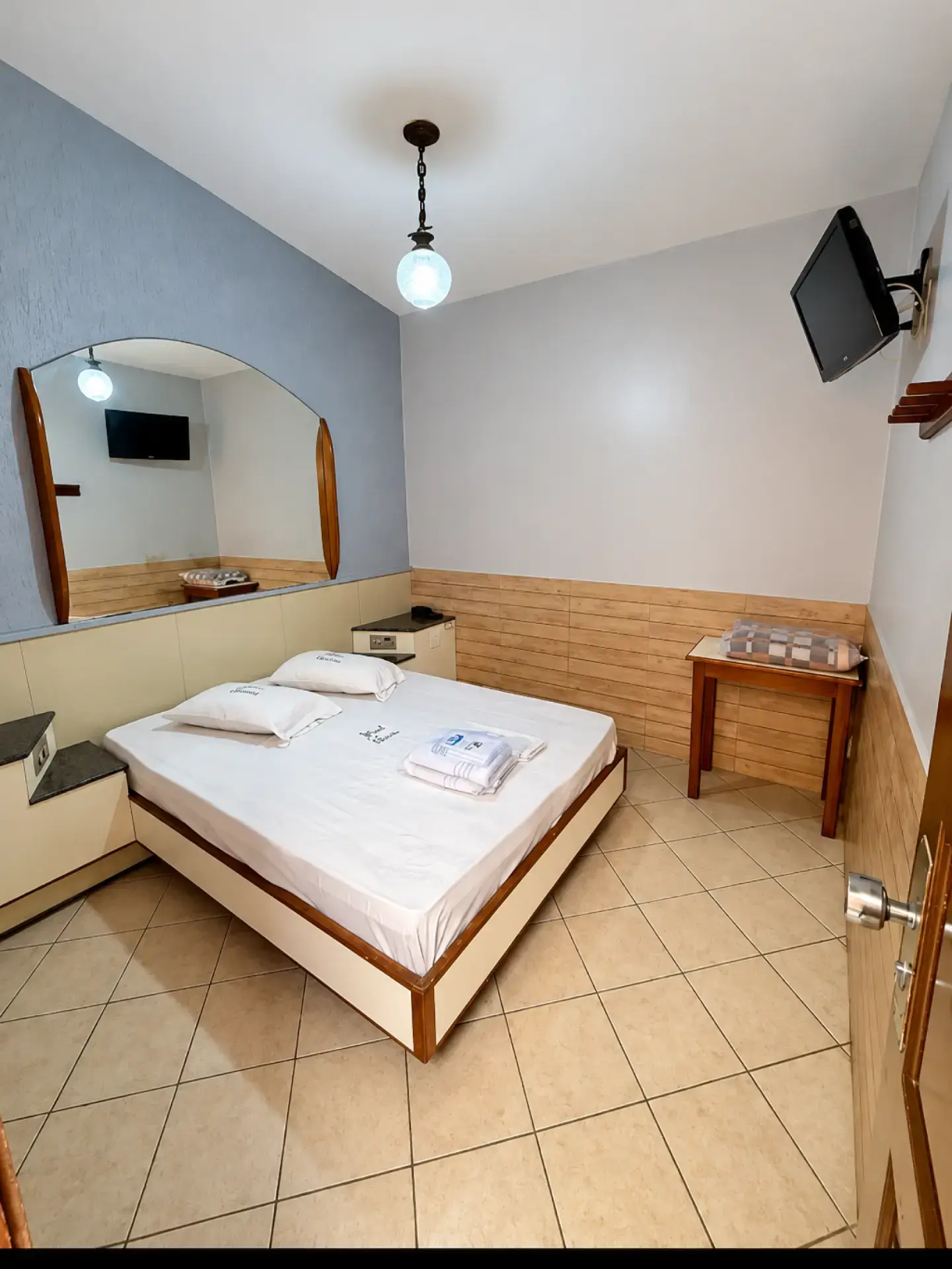 Suite with full bed, large mirror and wall-mounted TV